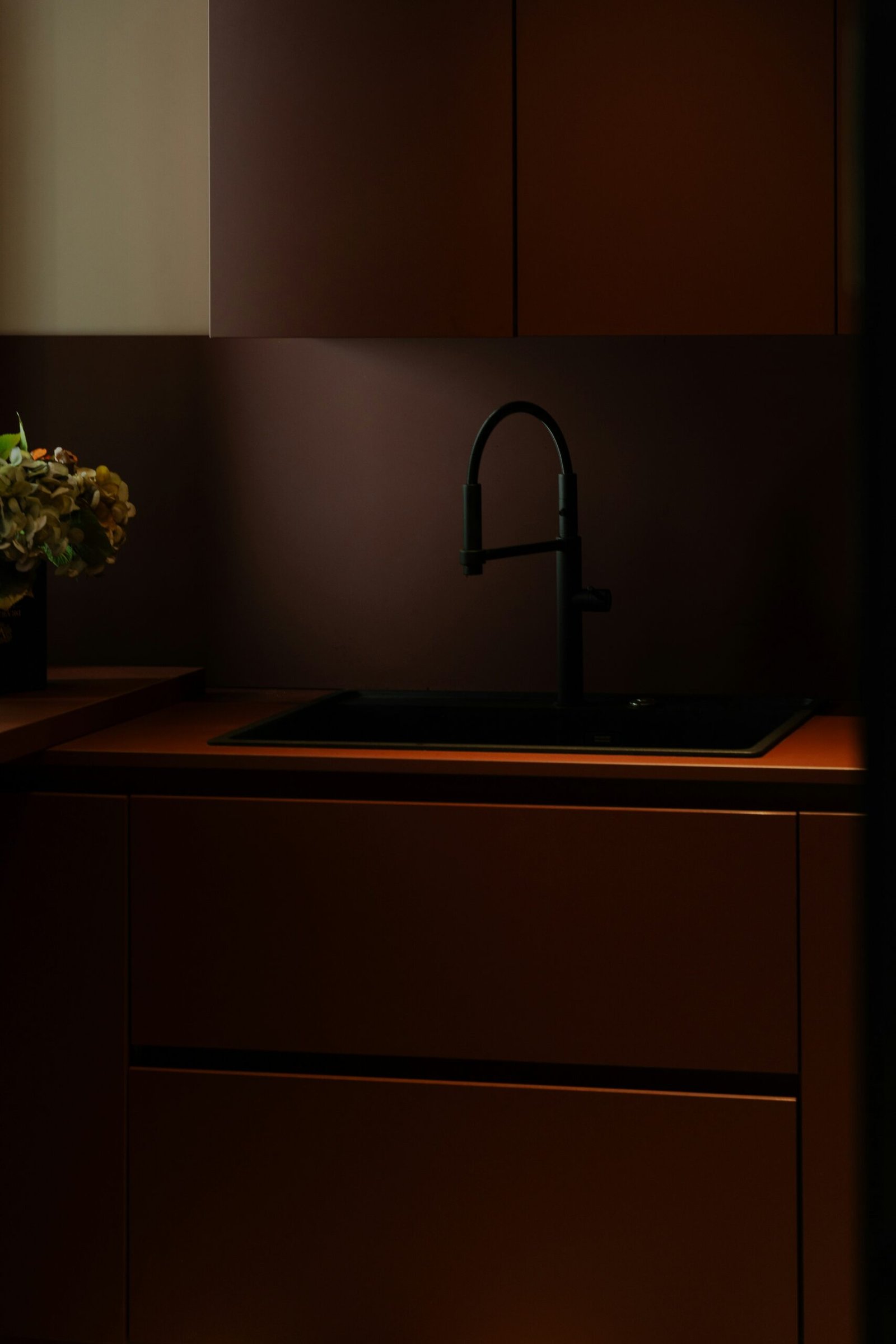 a kitchen with a sink, cabinets and a vase of flowers