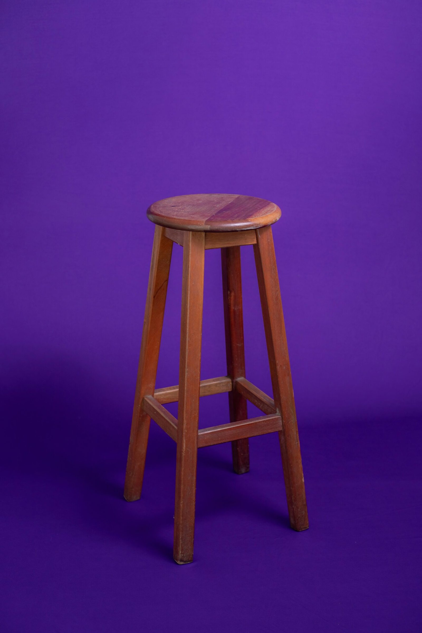 A wooden stool against a purple background