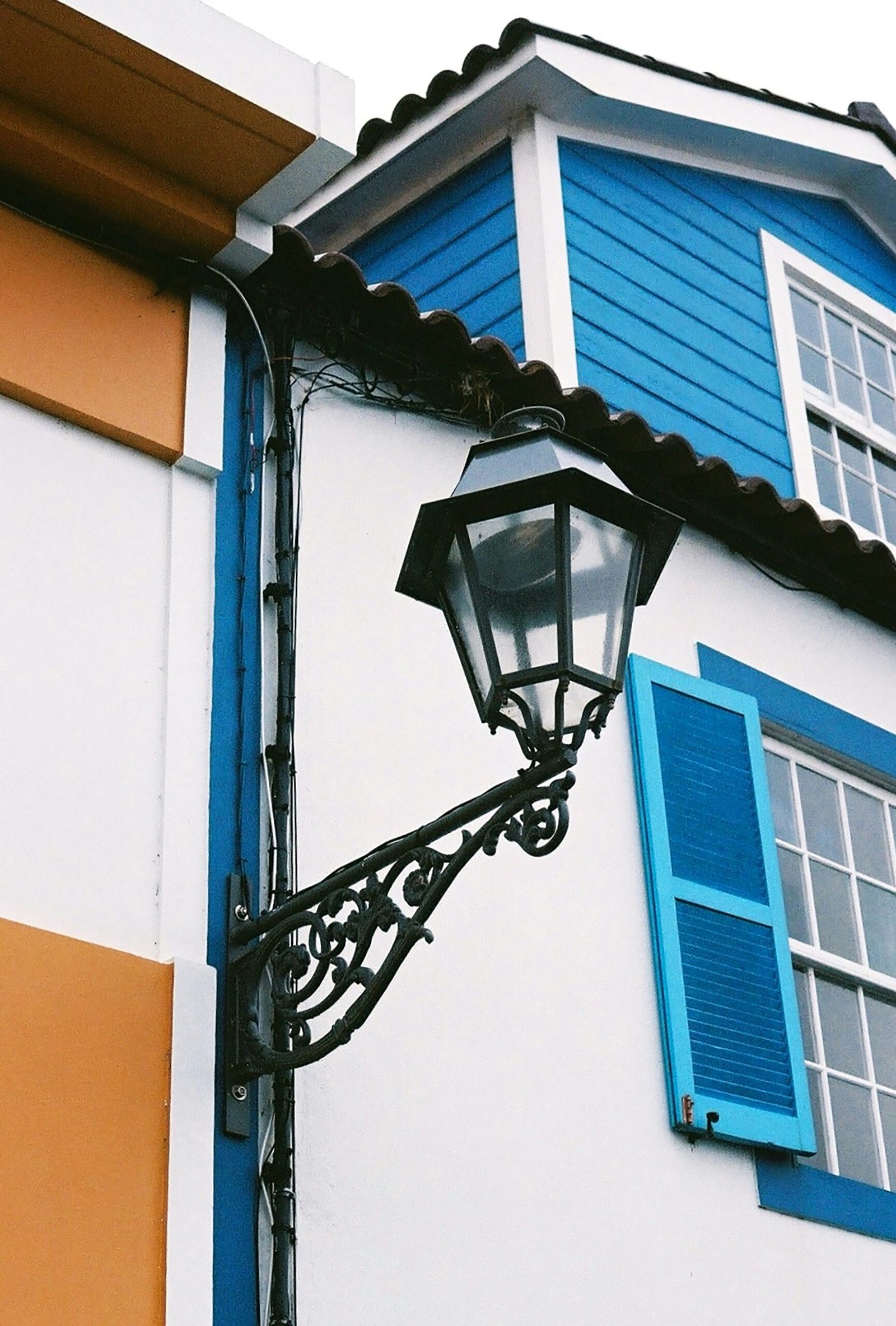 a street light next to a building with blue shutters